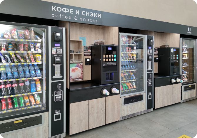 Alignement de plusieurs distributeurs automatiques et de machines à café, offrant une large gamme de snacks et boissons pour les entreprises ainsi que de savoureux cafés.